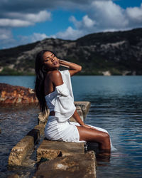 Woman sitting in sea against sky