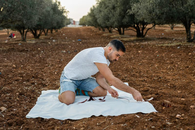 Side view of boy sitting on field