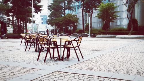 Chairs and tables arranged on street at cafe in city