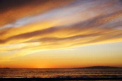 Scenic view of sea against dramatic sky during sunset