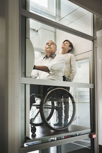 Son and father in wheelchair lift at home