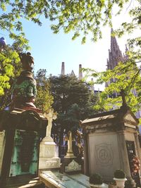 Statue amidst trees and buildings against sky