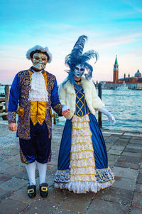 Man and woman wearing costume and mask against gondolas during venice carnival