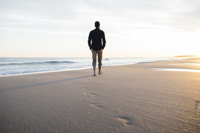 Rear view of man walking at beach