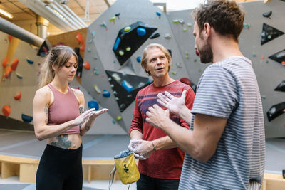 Mature trainer training male and female students for wall climbing in gym