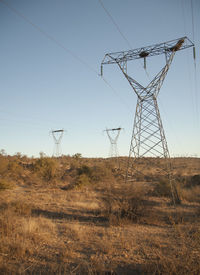 Low angle view of electricity pylon on field
