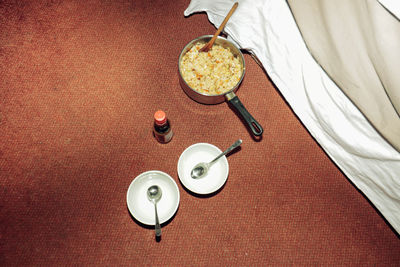 High angle view of food in a pan and two plates in the carpet