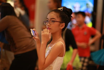 Side view of teenage girl looking away while holding mobile phone at home