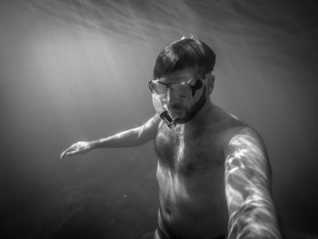 Shirtless man swimming in sea