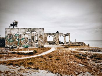 Abandoned built structure by sea against sky