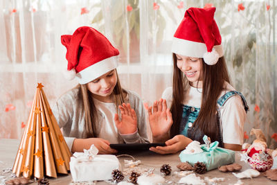 Girls in christmas decorations greet and communicate with their families through a tablet.