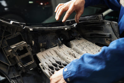 Hands of the master in cars and various car parts. car engine, bumper, metal parts of the car.