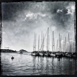 Boats in lake against cloudy sky