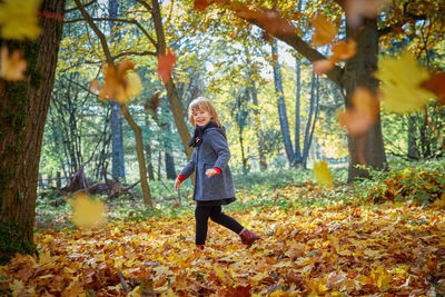 Full length of woman with autumn leaves in forest