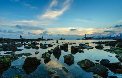 Scenic view of rocky beach against cloudy sky