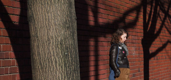 Close-up of woman standing against brick wall