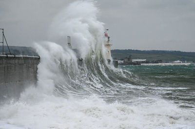 Waves splashing on shore against sky