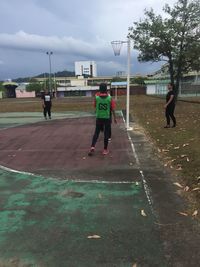 Rear view of people playing soccer against sky