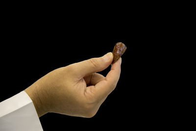 Close-up of person holding gemstone against black background
