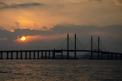 Bridge over sea against sky during sunset