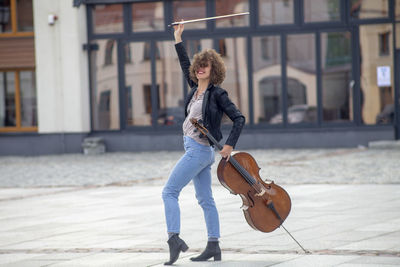 Smiling woman holding violin while dancing on street