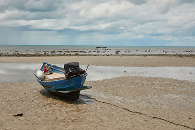 Boat moored on beach against sky