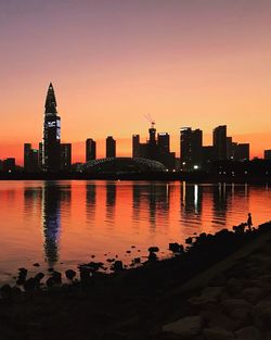 Scenic view of river and buildings against sky during sunset