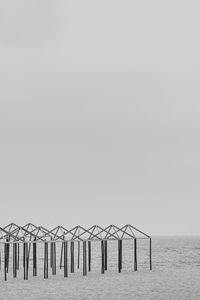 Wooden posts in sea against clear sky