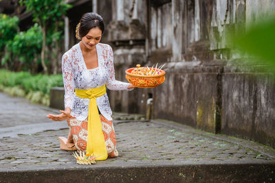 Portrait of young woman standing on footpath