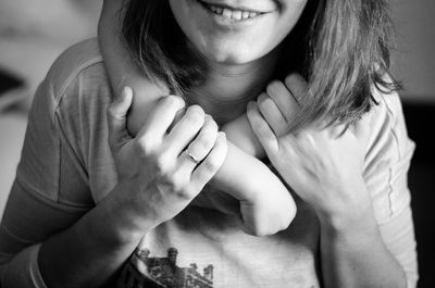 Cropped hands of child around mother neck at home