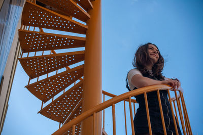 Low angle view of woman standing on steps against sky