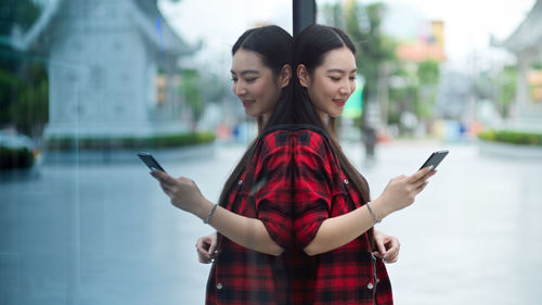 Friends standing on mobile phone in city