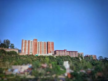 Buildings in city against clear blue sky