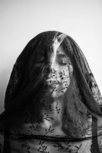 Young woman wearing transparent scarf against wall at home