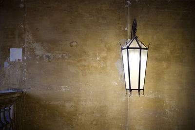 Illuminated lamp hanging on wall at home