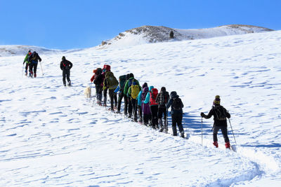 People on snowcapped mountain against sky