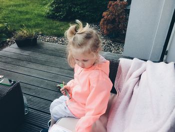 High angle view of girl sitting on sofa at yard