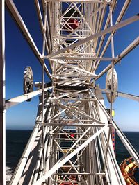 Ferris wheel by sea against clear blue sky