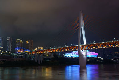 Illuminated bridge over river at night