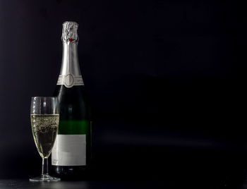 Glass bottle on table against black background