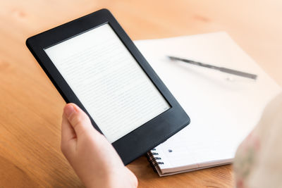 Low section of person holding smart phone on table