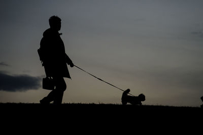 Silhouette man standing on field against sky during sunset