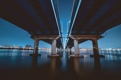 Bridge over river against sky in city at night