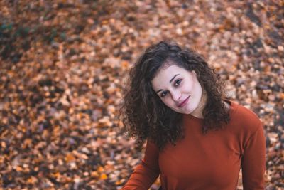 Portrait of smiling young woman standing on field in autumn