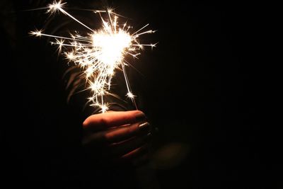 Hand holding illuminated lighting equipment against black background