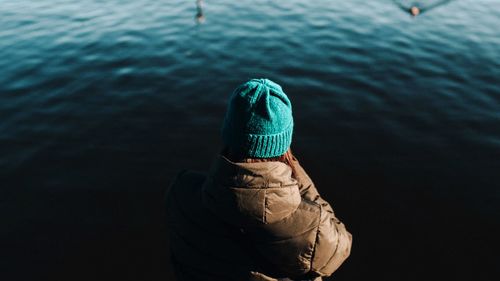 Rear view of woman by lake during winter