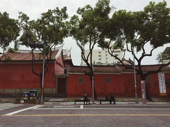 People sitting on bench by street against houses in town