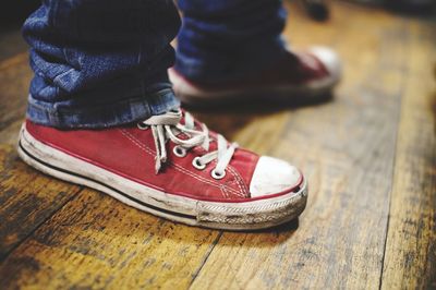 Low section of person wearing red canvas shoes