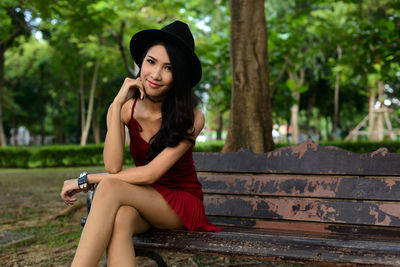 Young woman looking at camera while sitting on mobile phone