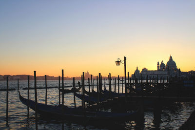 Boats moored in canal at sunset